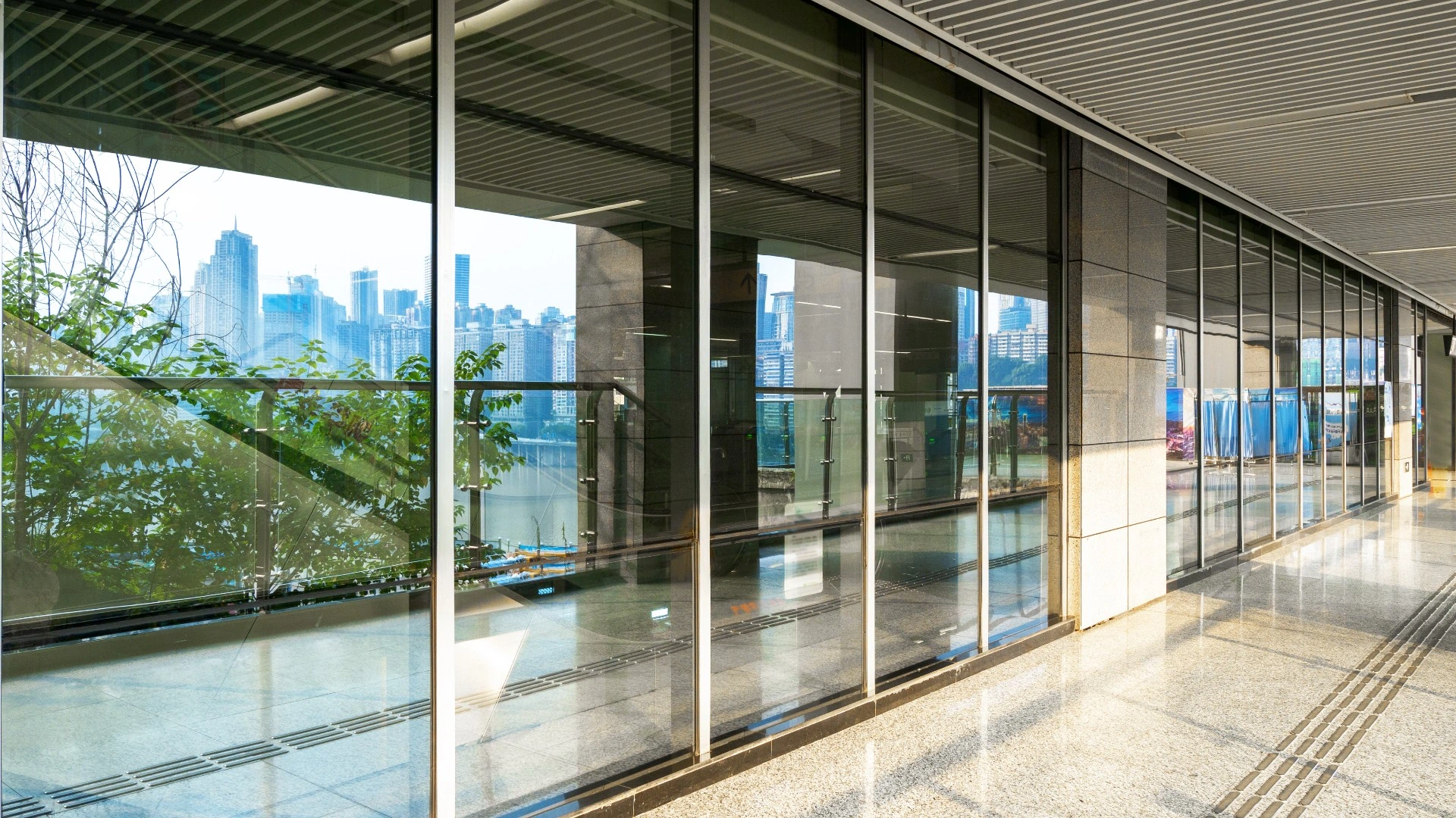 A bright hallway lined with glass walls, providing a clear view of the bustling city outside.