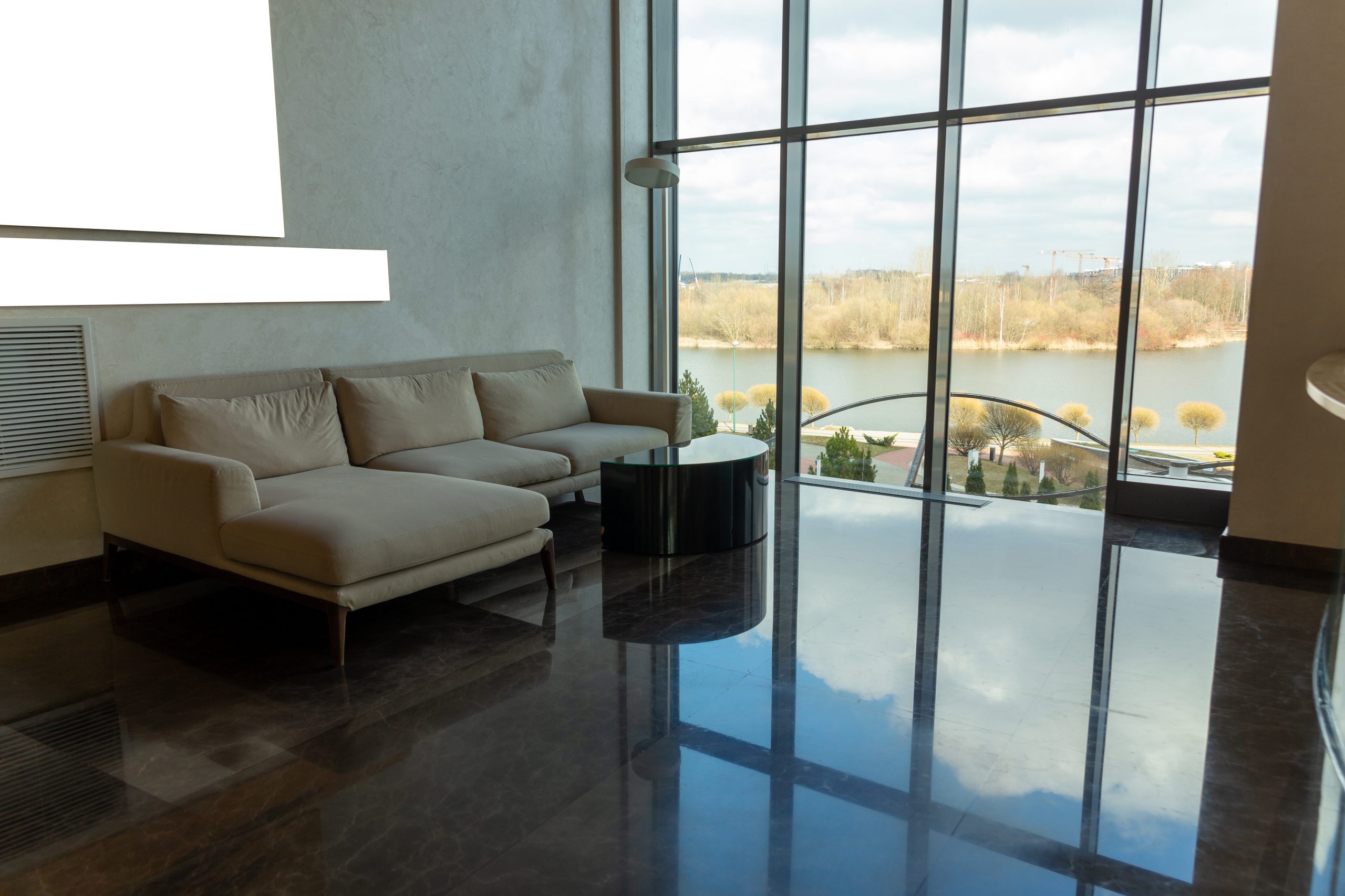 Luxury comfortable lounge with beautiful view on river coast, comfortable couch. Corner sofa in front of a huge window in modern hotel.