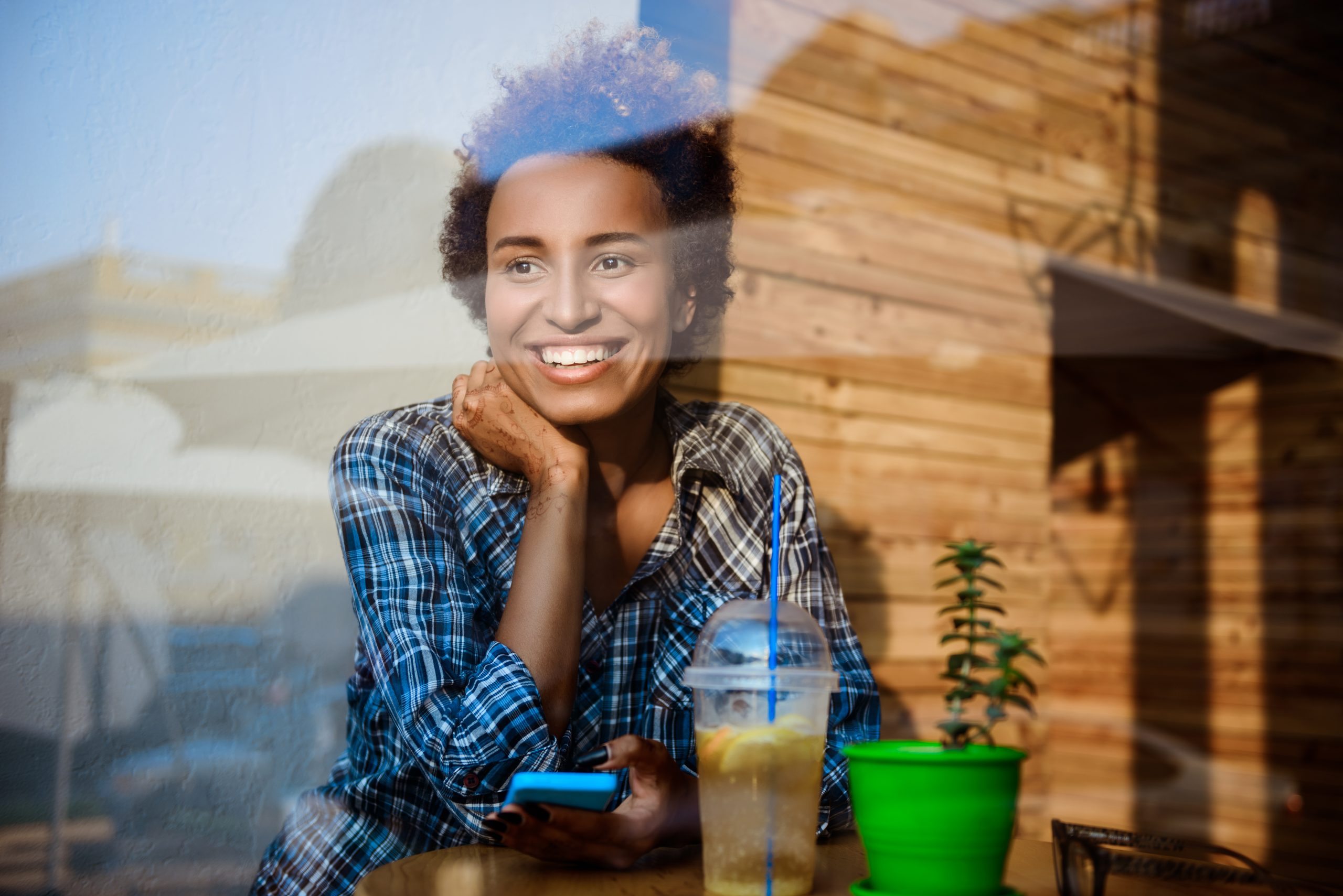 1. A woman smiles at a table, enjoying a drink in a relaxed setting.
